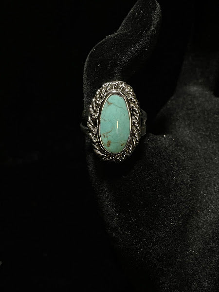 Turquoise ring — side view on black velvet, the pale oval stone smooth in its rope bezel above the split shank