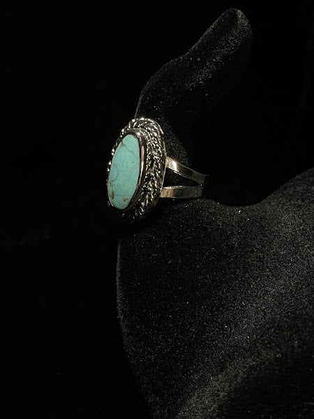 Turquoise ring — side view of the pale blue-green oval stone in its rope bezel on a black velvet hand form