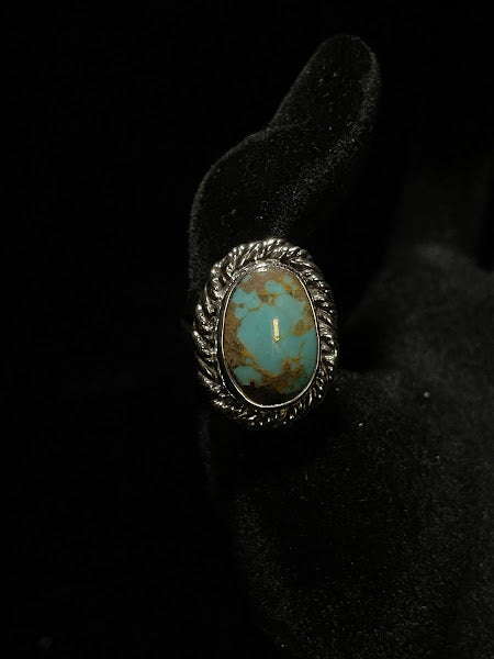 Turquoise ring — three-quarter view of the pale blue oval stone with fine speckles, rope bezel, on black velvet