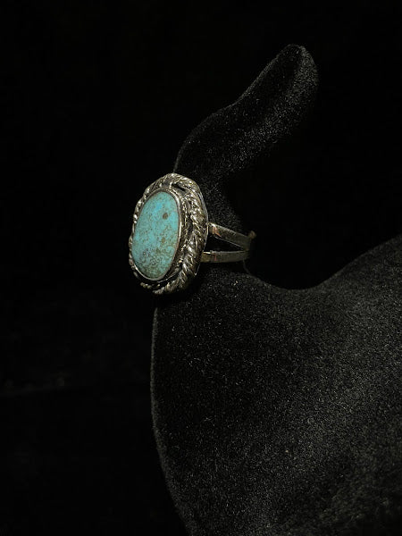 Turquoise ring — three-quarter view on black velvet, the oval stone face turned to the light above the split shank