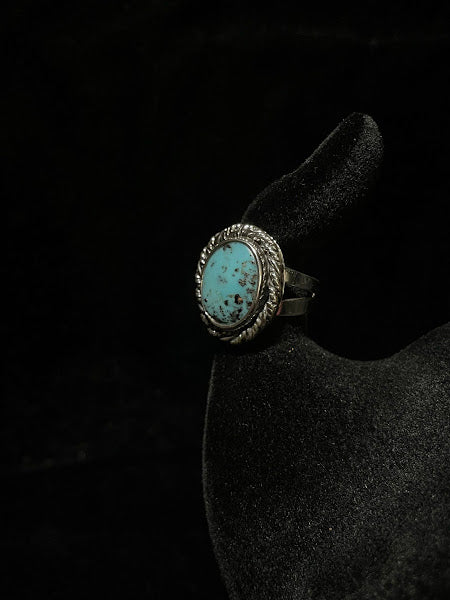 Turquoise ring — genuine Sonoran turquoise stone with dark speckles, sterling silver rope bezel, front view on black velvet