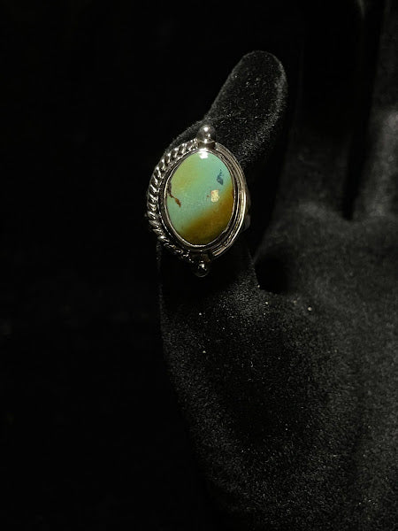 Turquoise ring — front view of one oval green-blue Sonoran turquoise stone, rope edge and two silver beads on black velvet