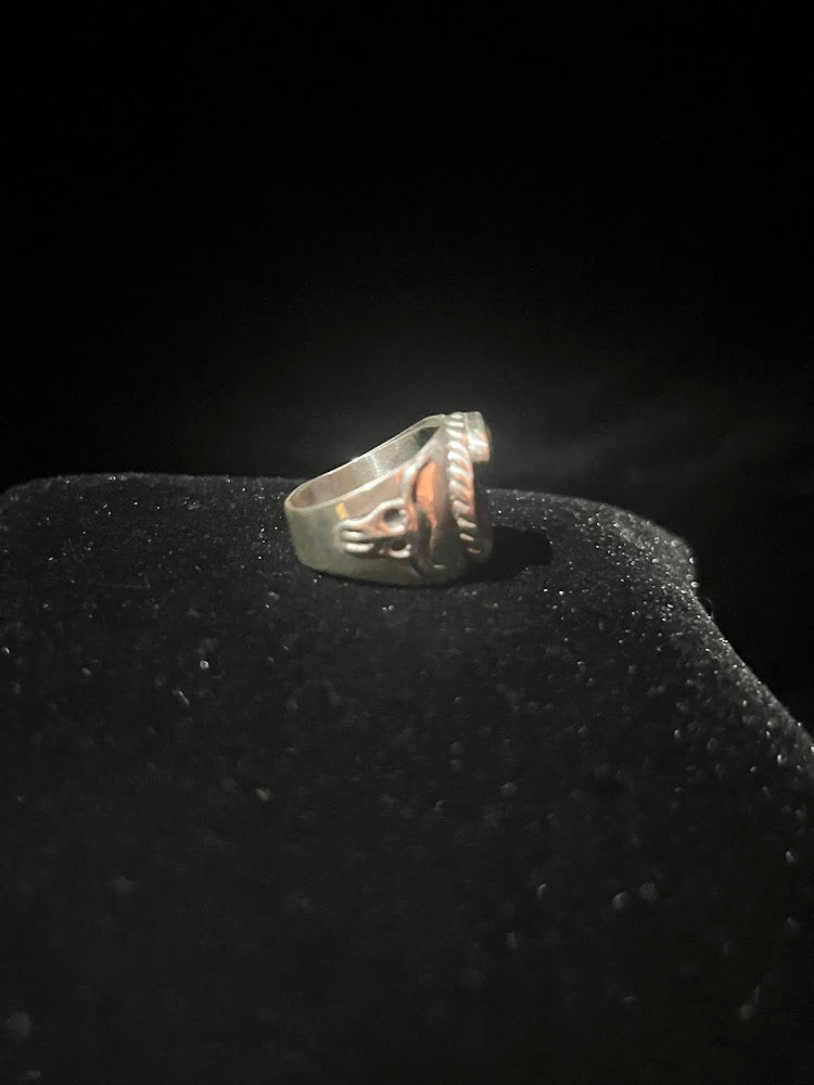Turquoise ring — side view showing the longhorn skull shoulder and rope edge of the sterling silver face, on black velvet