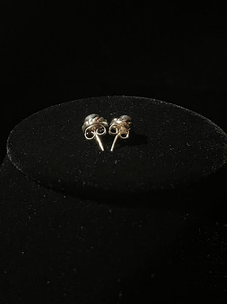 Turquoise stud earrings — posts and butterfly backs of the mini pair on a black studio stand