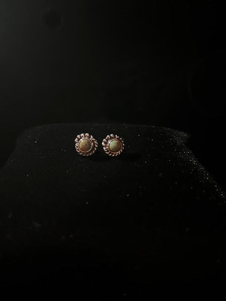 Turquoise stud earrings — the mini pair resting on black velvet, rope bezels and warm silver showing
