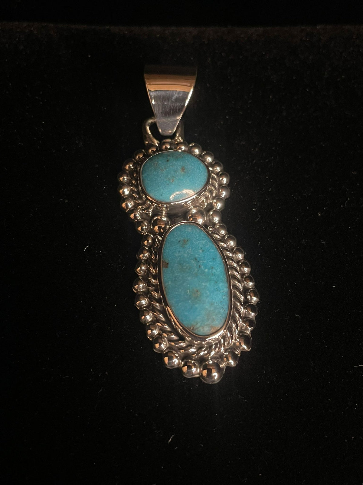 Two-stone turquoise pendant — front view of a vivid blue two-stone pendant, round over oval, on black velvet