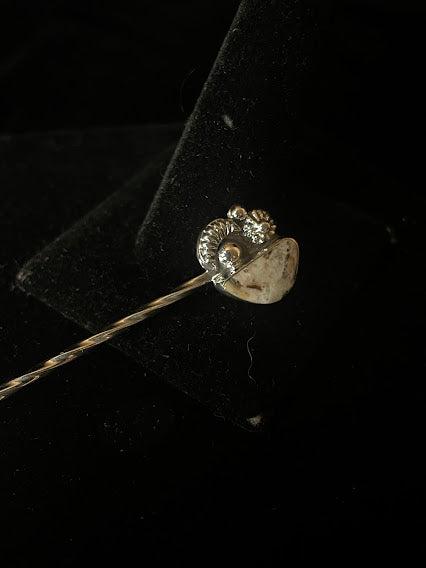White buffalo hat pin — the back of a one-stone pin, white buffalo in its bezel cup over shell-form silverwork