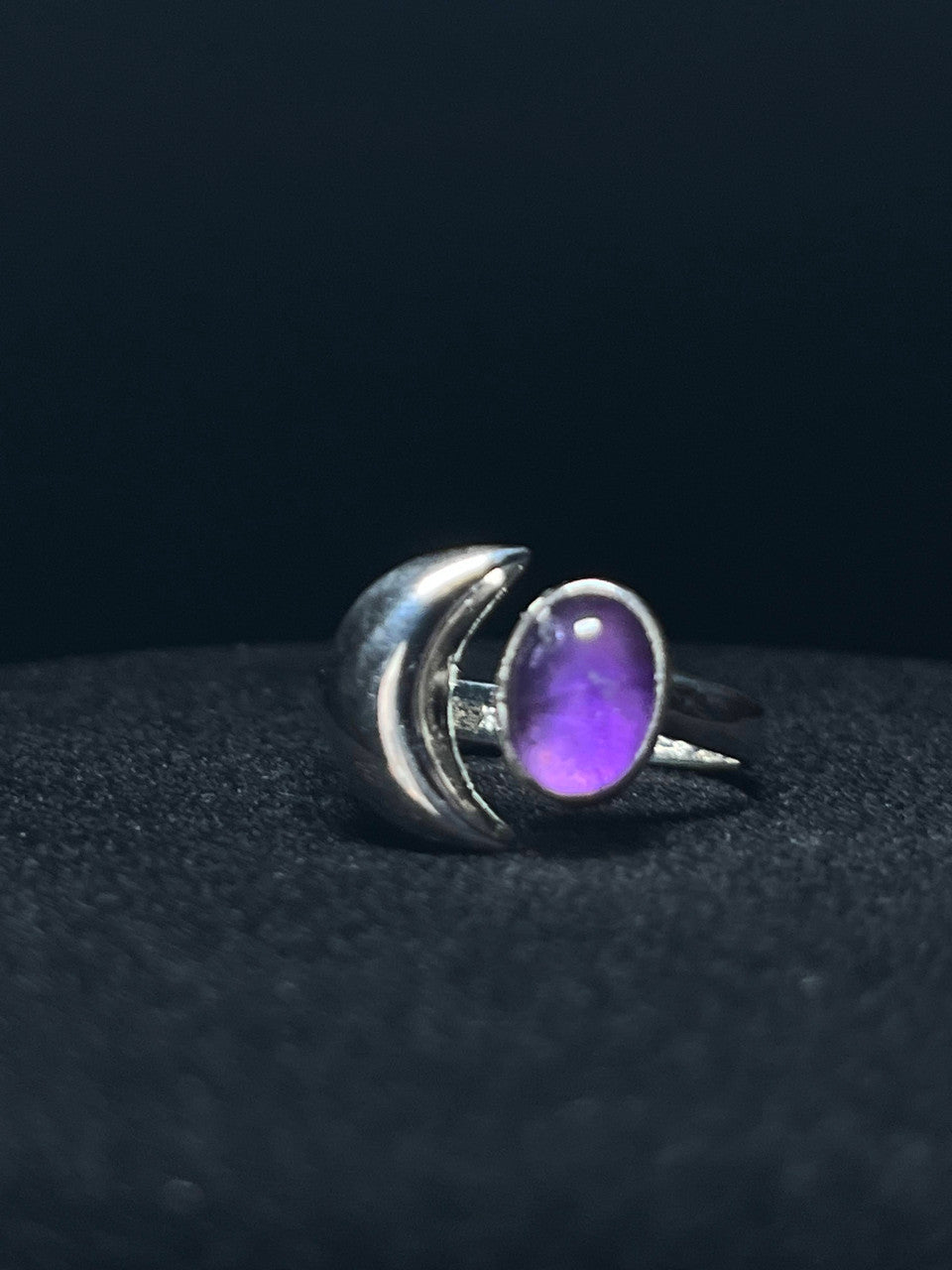 Crescent moon ring — purple amethyst oval held inside a sterling silver crescent, detail on black