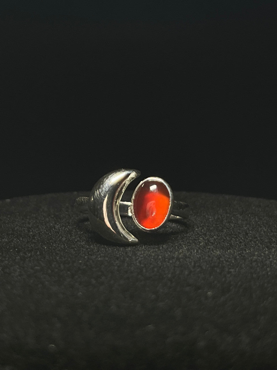 Crescent moon ring — red-orange carnelian oval beside a sterling silver crescent moon on black