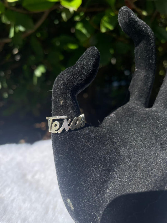 Mens sterling silver rings — Texas script ring worn on a black hand display outdoors, script Texas lettering