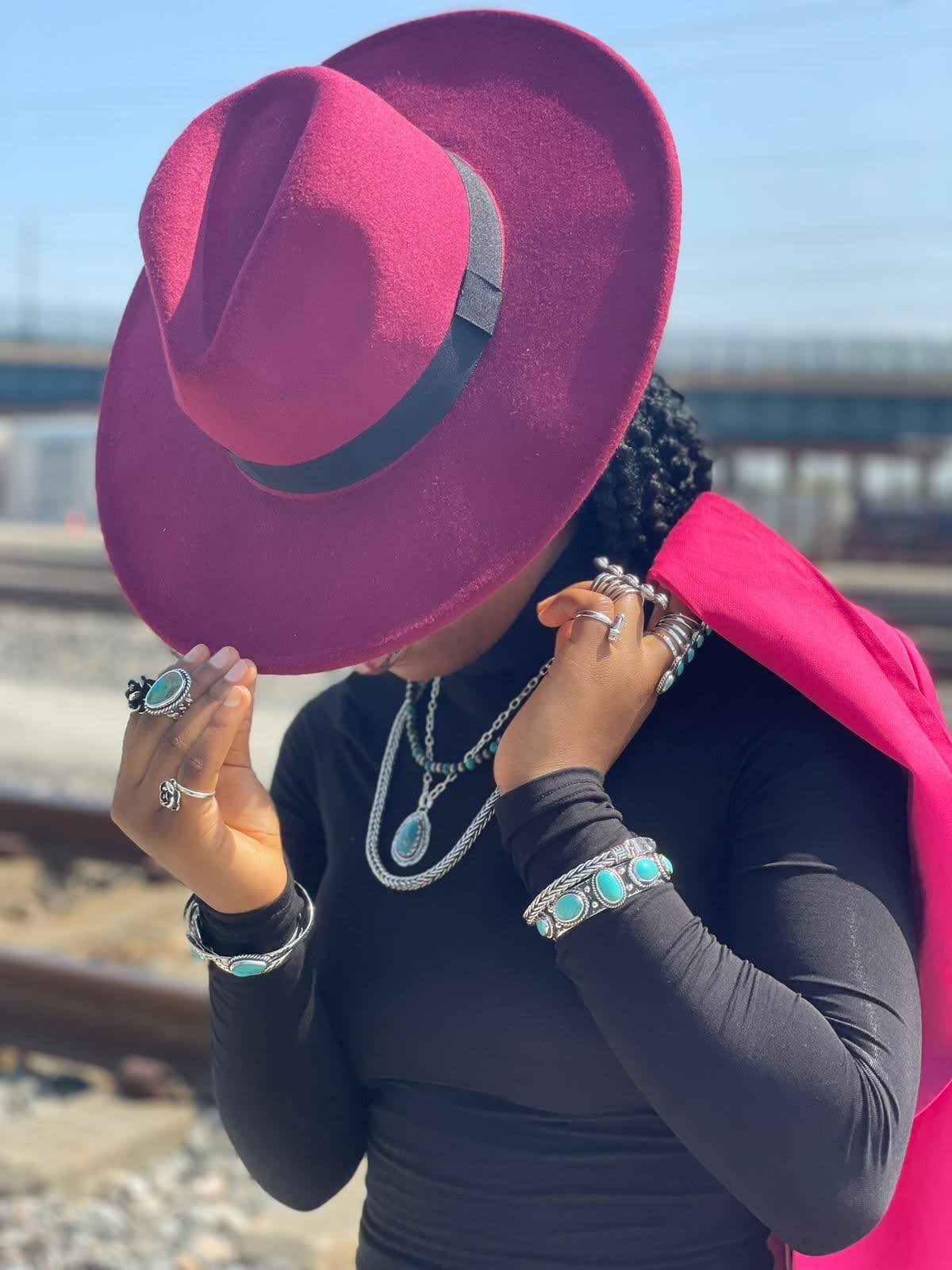 Turquoise cuff — worn on a wrist outdoors with layered sterling jewelry and a deep pink hat, railroad setting