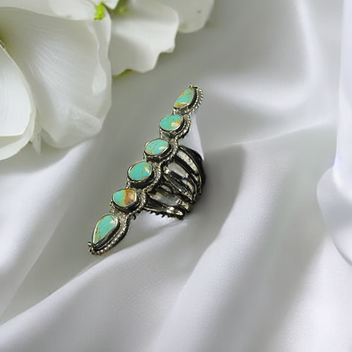 Turquoise ring — close view of six turquoise stones with golden-brown matrix on white satin beside a white flower