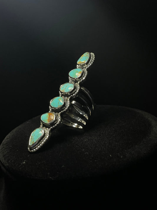 Turquoise ring — six genuine Sonoran turquoise stones in a long row, sterling silver rope bezels, front view on a black stand